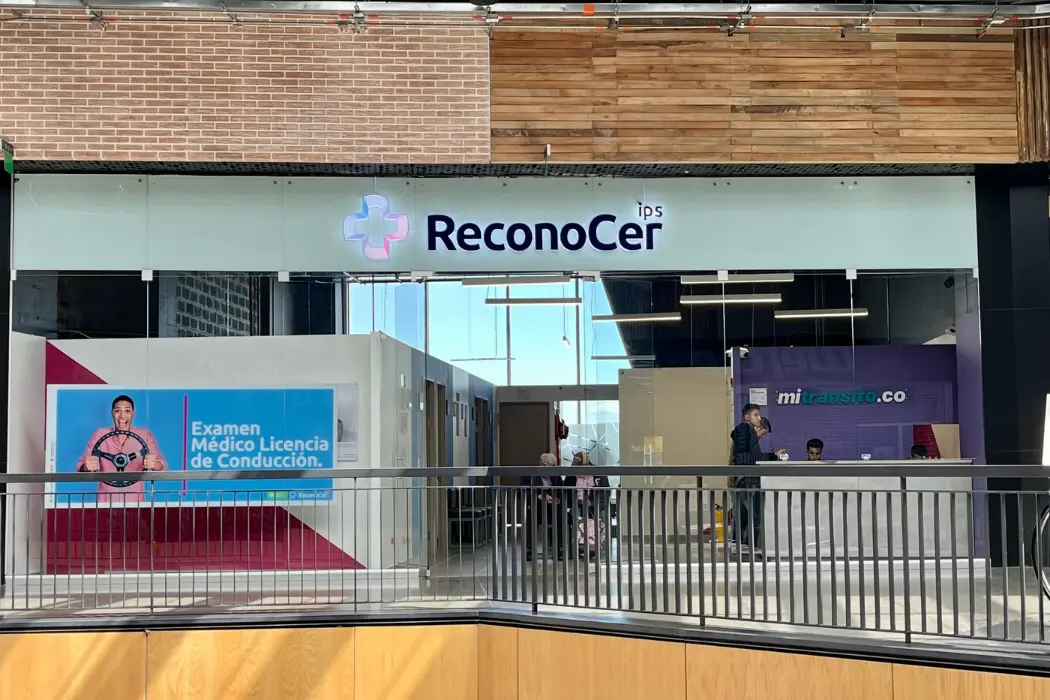 Fachada de ReconoCer IPS en el centro comercial Nuestro Bogotá: letrero iluminado sobre el local acristalado y, a la derecha, el mostrador de mitransito.co
